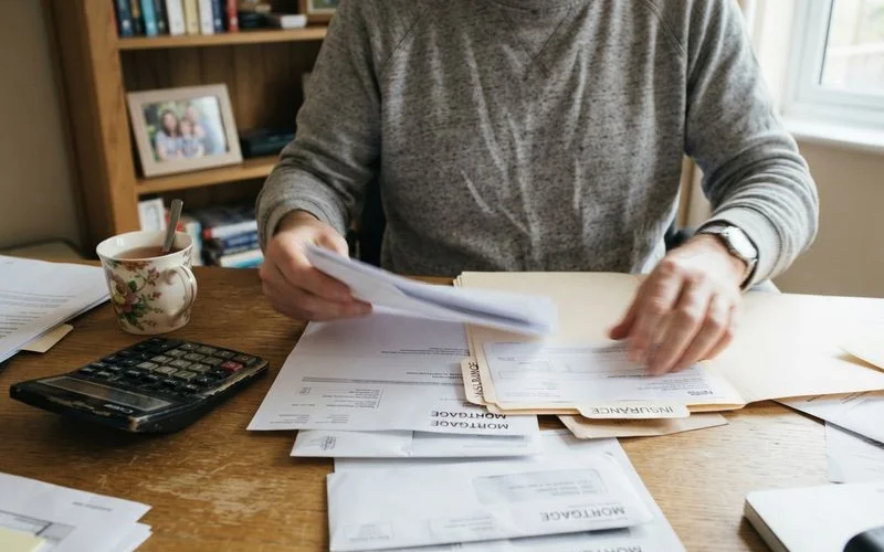 A person sorting through mail and mortgage documents at home during a difficult personal transition